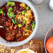 A bowl of homemade beef chili with melted cheddar cheese, sour cream, and fresh cilantro on top