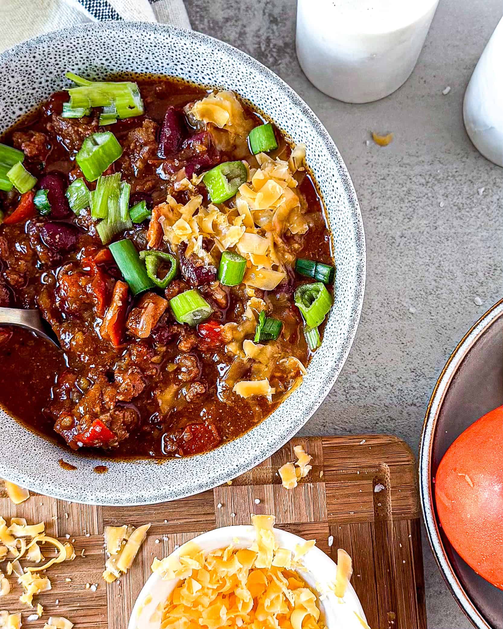 A bowl of homemade beef chili with melted cheddar cheese, sour cream, and fresh cilantro on top