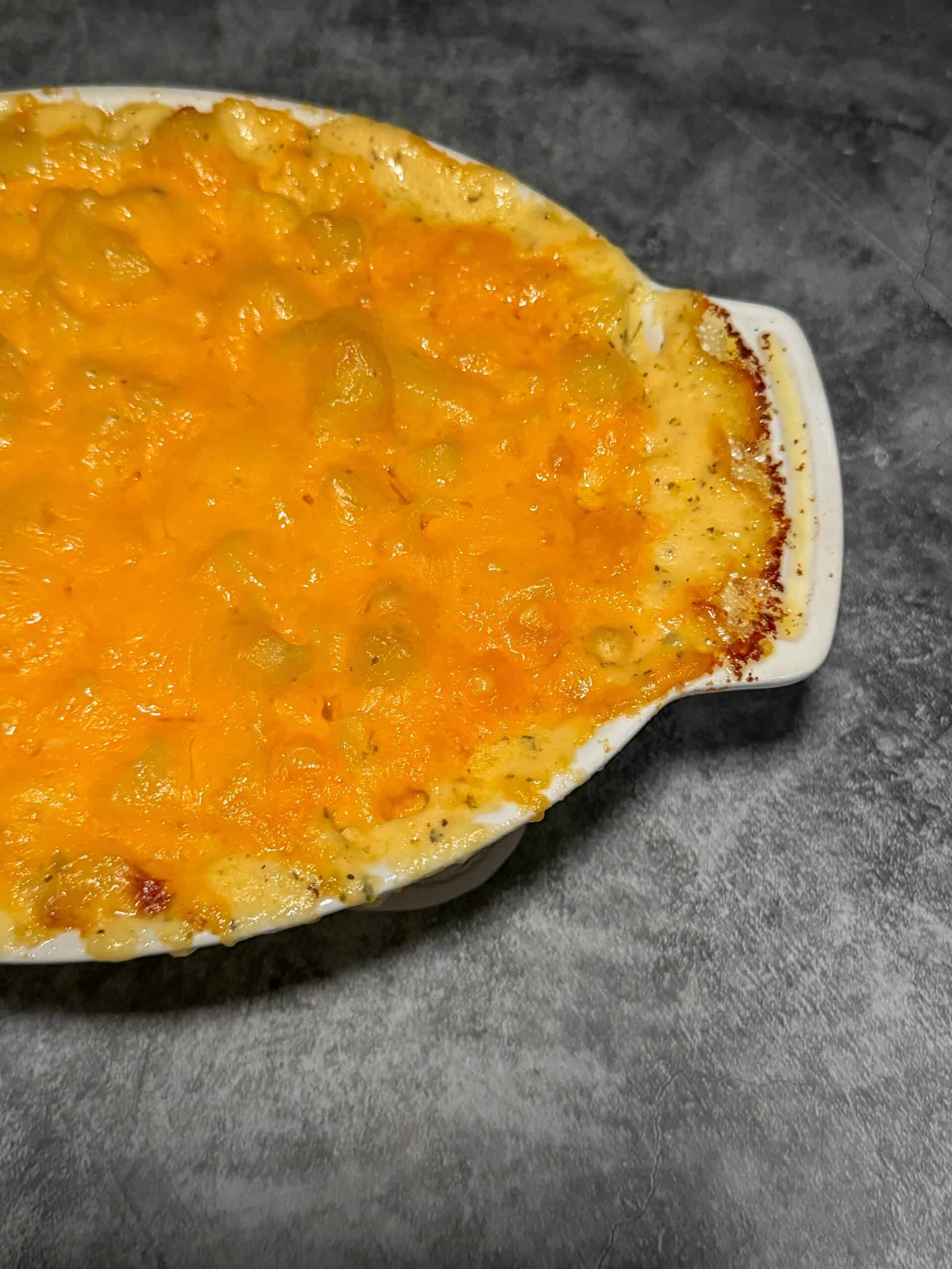 Creamy four cheese mac and cheese in white baking dish with golden bubbly cheese on top