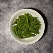 Garlic green beans in a white serving dish with visible garlic pieces and olive oil