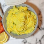 Creamy herb mashed potatoes with fresh parsley and chives in a white serving bowl