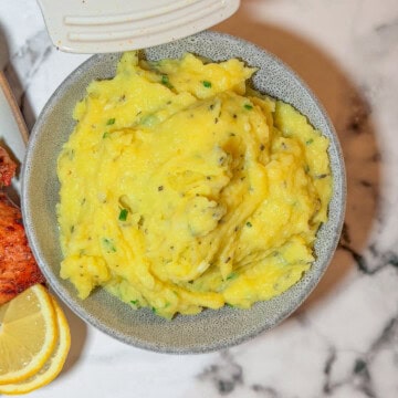 Creamy herb mashed potatoes with fresh parsley and chives in a white serving bowl
