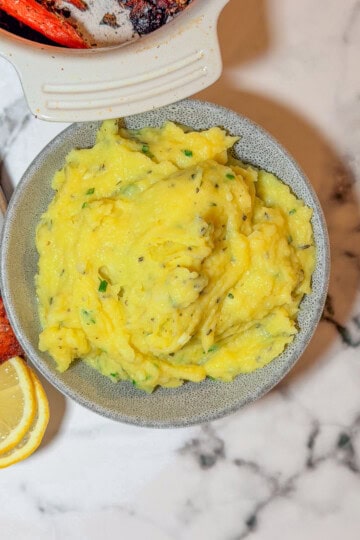 Creamy herb mashed potatoes with fresh parsley and chives in a white serving bowl