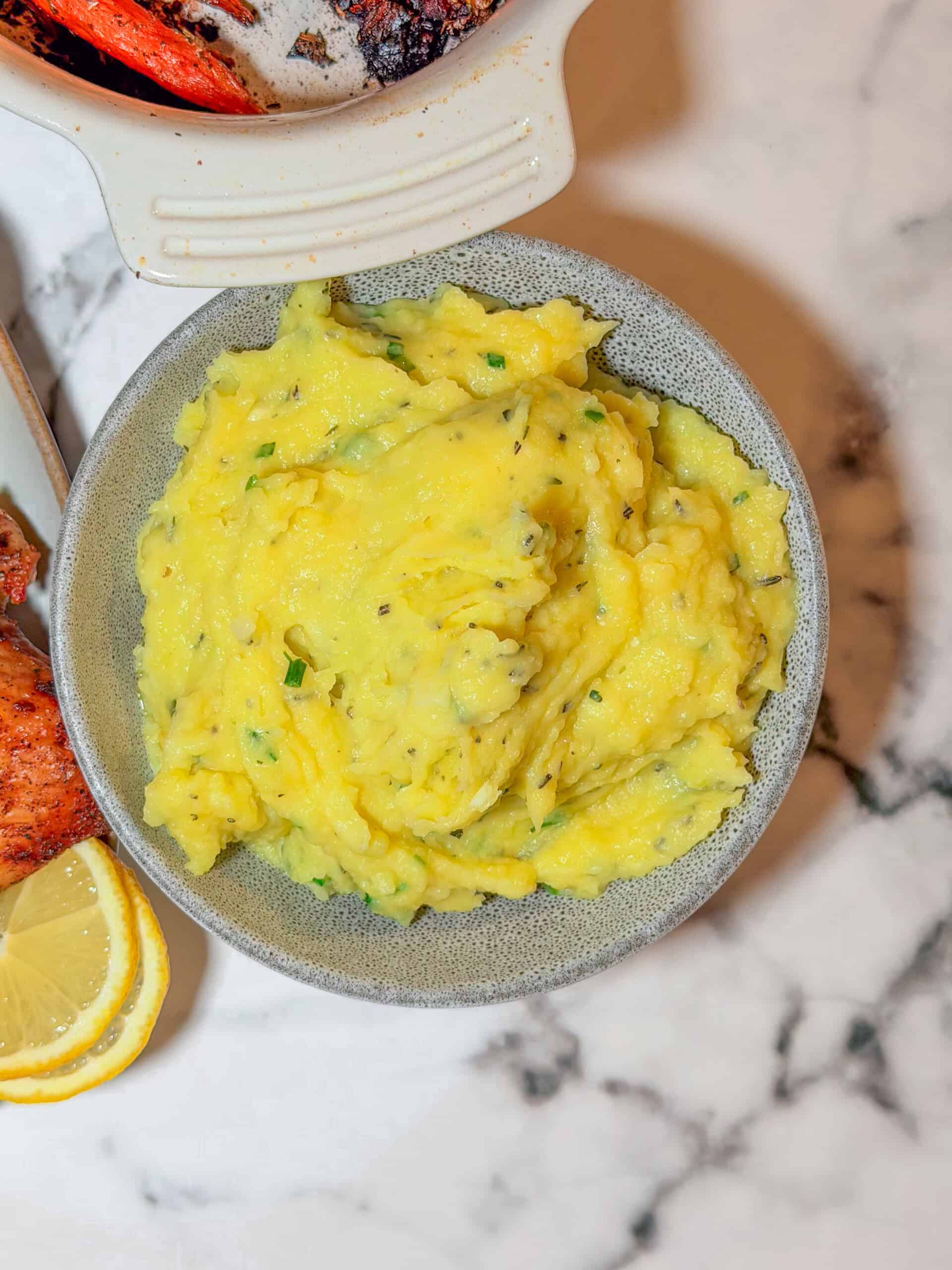 Creamy herb mashed potatoes with fresh parsley and chives in a white serving bowl