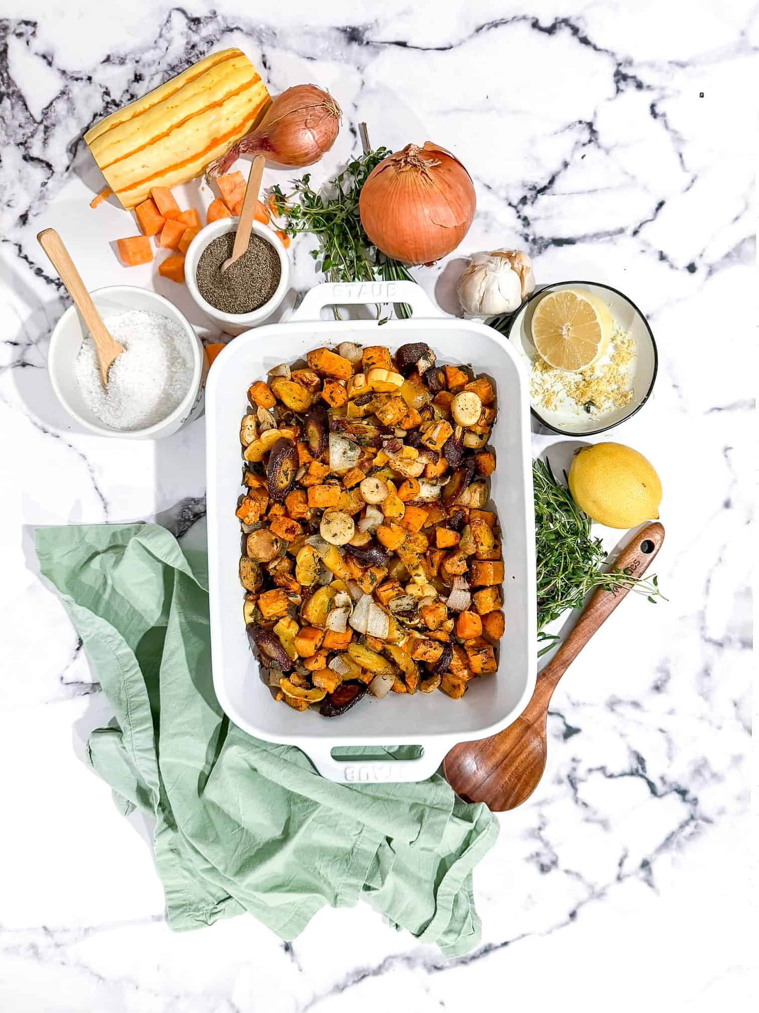 Roasted root vegetables topped with a whole roasted chicken on a baking sheet