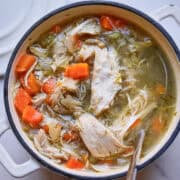Bowl of homemade chicken noodle soup with shredded chicken, egg noodles, and fresh dill in golden broth
