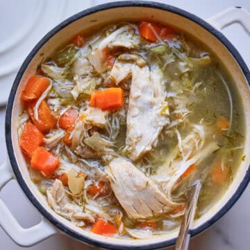Bowl of homemade chicken noodle soup with shredded chicken, egg noodles, and fresh dill in golden broth