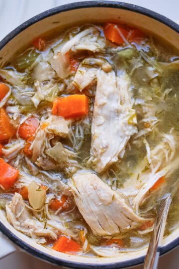 Bowl of homemade chicken noodle soup with shredded chicken, egg noodles, and fresh dill in golden broth